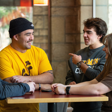 A group of UW peer-mentors meet together and have a discussion at an on-campus cafe.