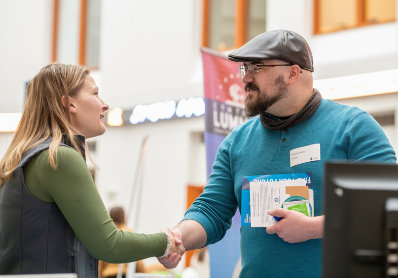 A UW student shakes hands with a potential employer at a UW career fair as part of ACES career counseling.