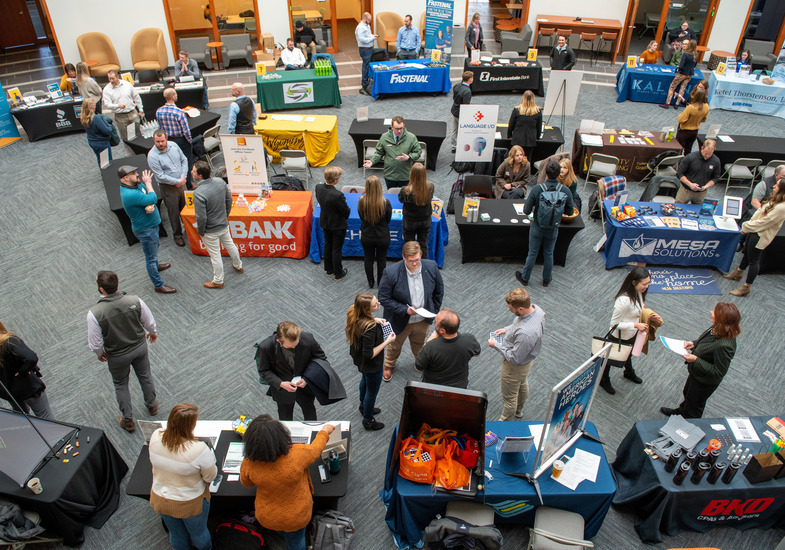 Aerial image of a career fair in the College of Business Jonah Bank Atrium of employer booths and people talking
