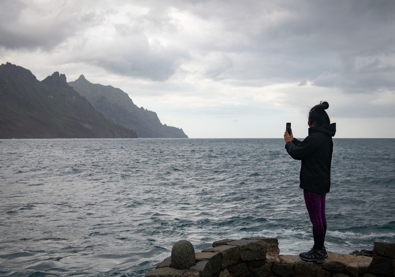 A study abroad student standing in front of a cold ocean taking a picture.