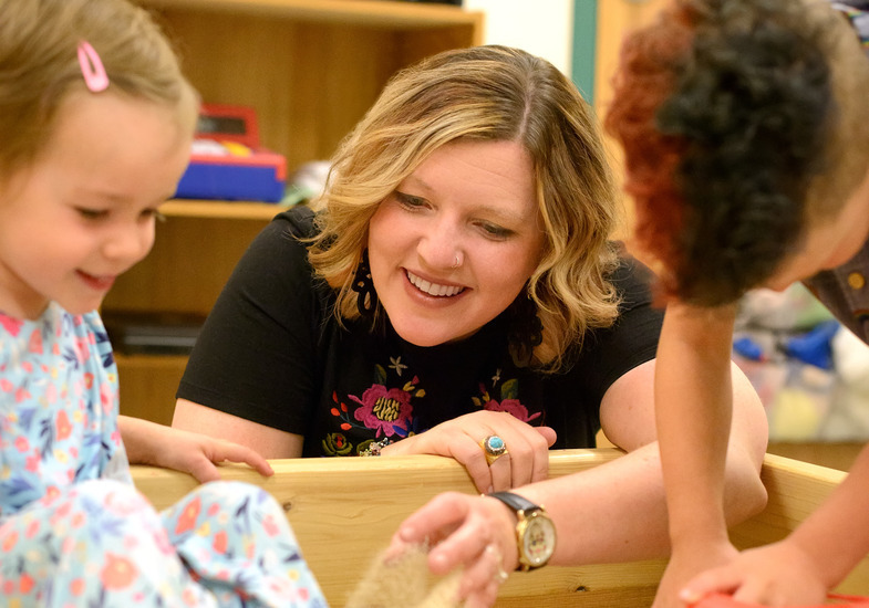 teacher working with children in a sandbox