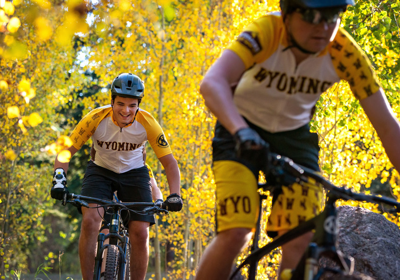 A student athlete on a mountain bike riding through the forest