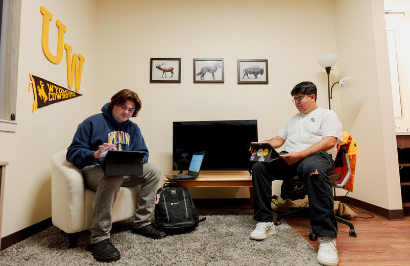 Two students sitting in the new UW residence halls looking at their tablets