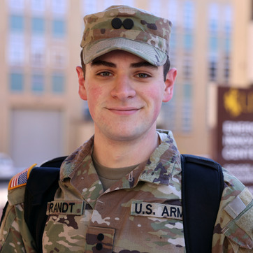 A UW military student dons fatigues as they smile on the University of Wyoming campus.