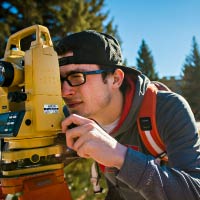 A student looks through a surveying instrument.