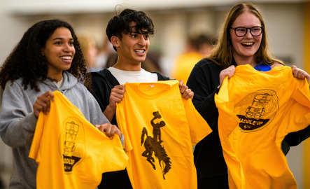 UW freshmen happily holding up their new UW spirit shirts at an admissions event.