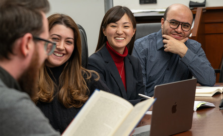 UW students smile as they sit around a table having an academic discussion.