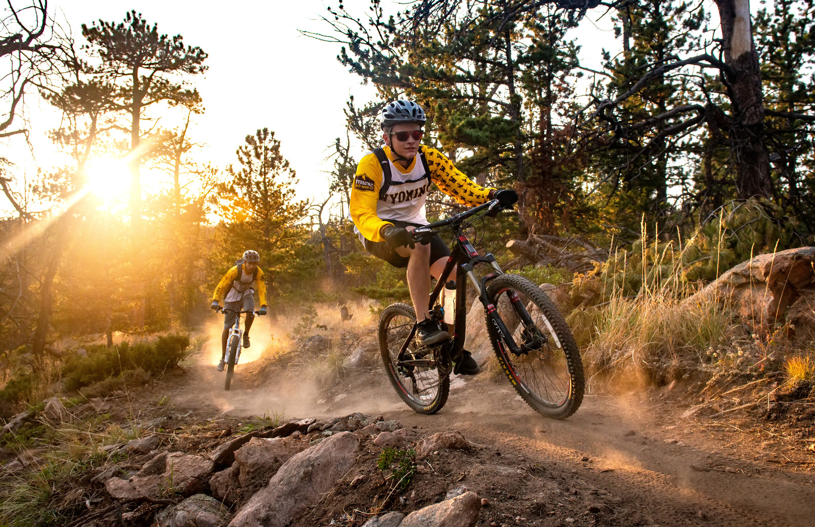 two people on maountain bikes wearing helmets surrounded by fall leaves