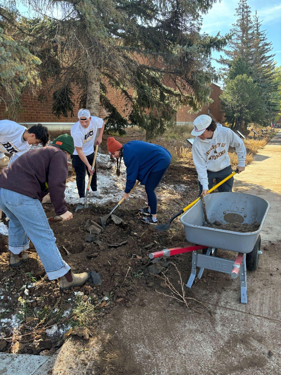 Students shoveling dirt into a wheel barrow