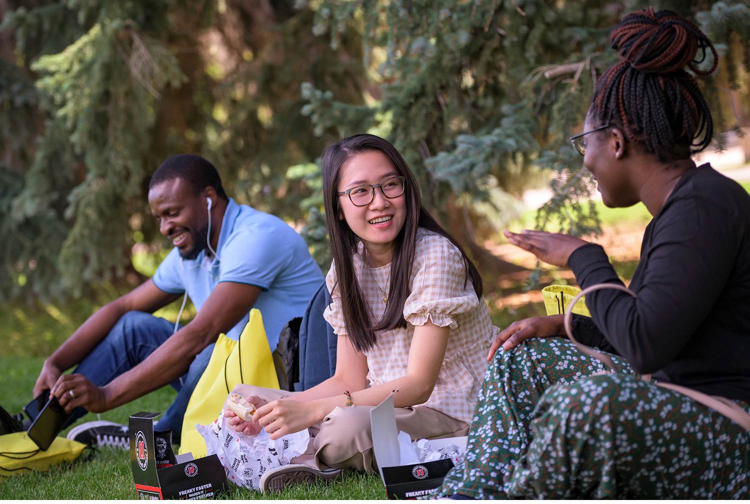 Some students sit by a tree talking.