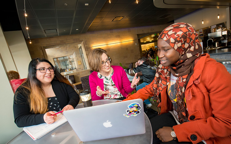 Students conversing with professor at table