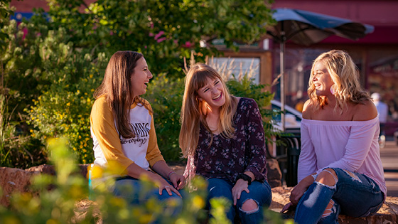 Three laughing students sitting in Downtown Laramie