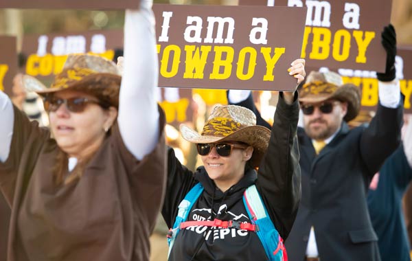People holding up Cowboy signs at homecoming parade