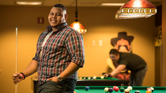 A Student standing in front of pool table in Pete's Game Room