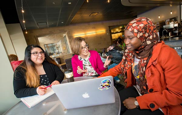 Professor and two students at table in cafe