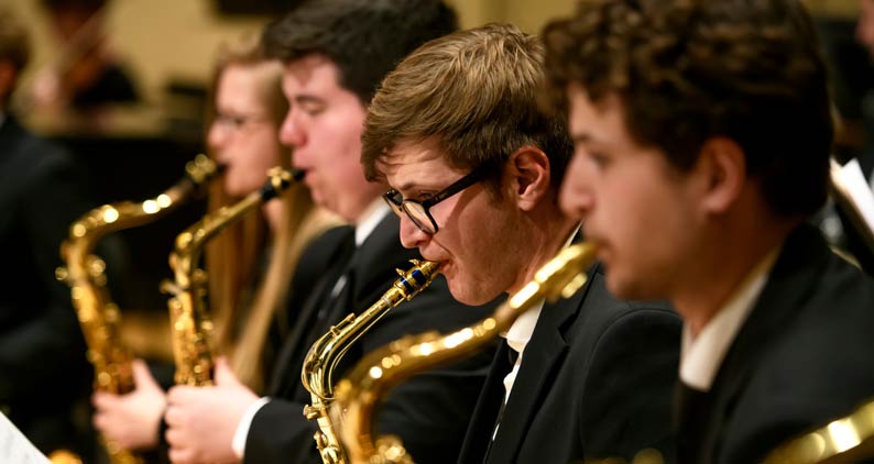 Students play the saxophone together at a concert.