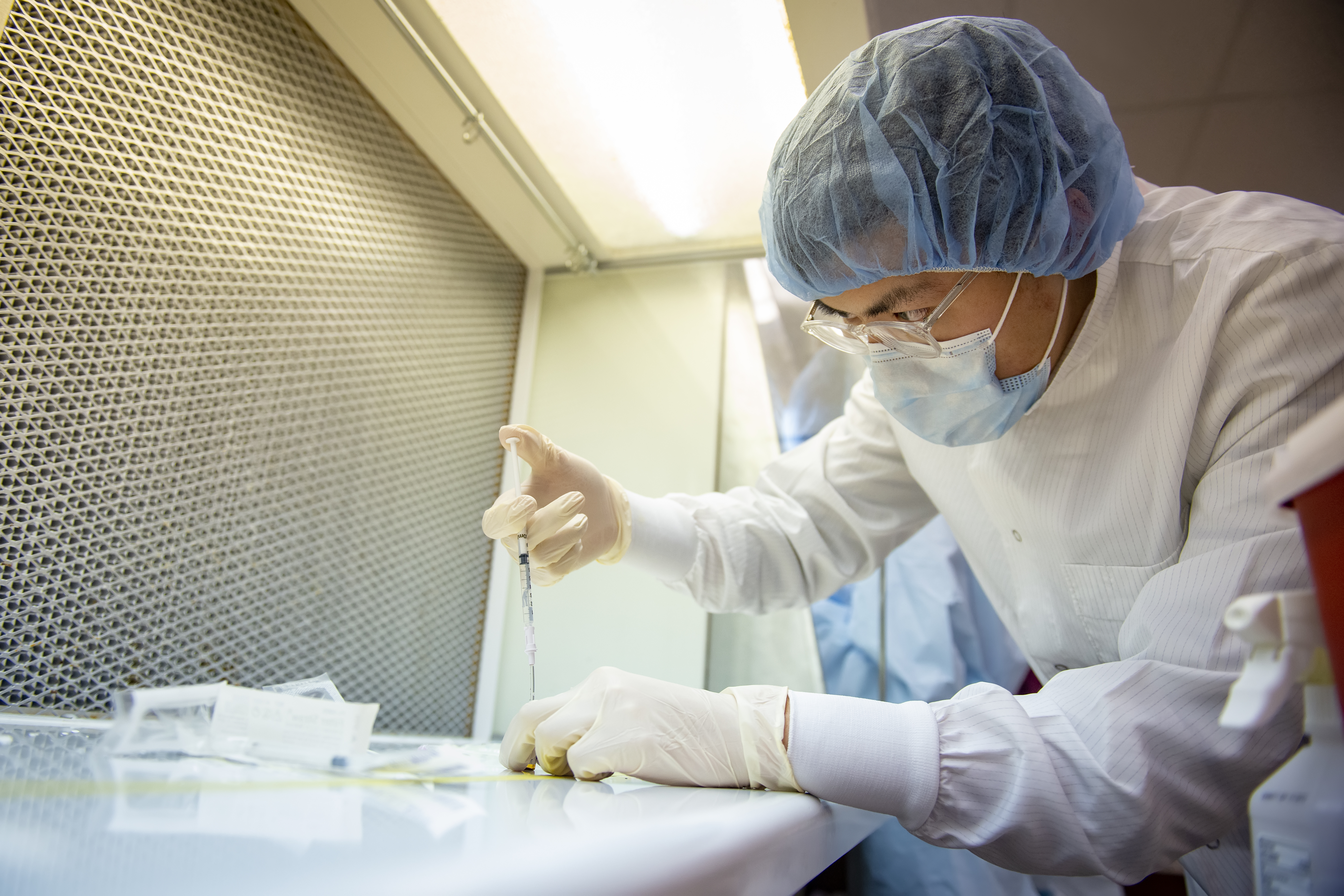 A student working in a science lab while wearing protective clothing and equipment