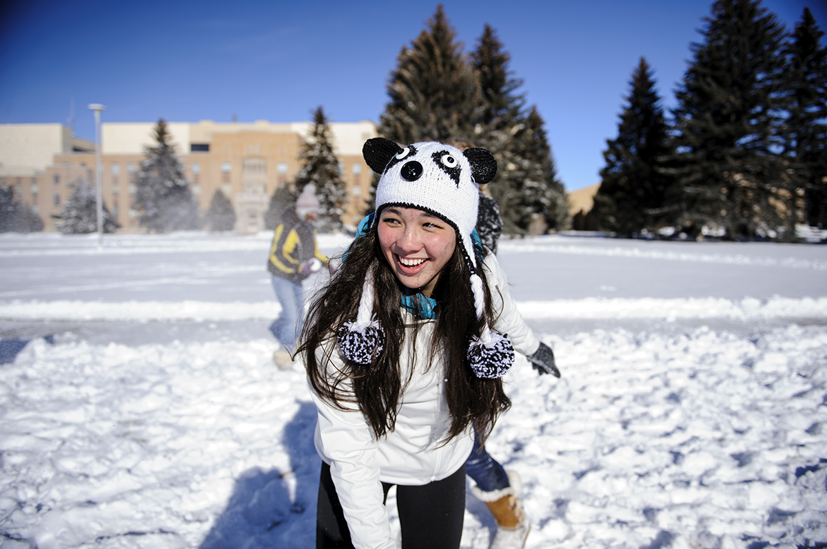 Student plays in snow while dressed warm