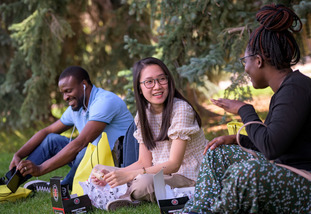 three students chat on campus