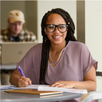 A graduate students smiles while sitting in class.