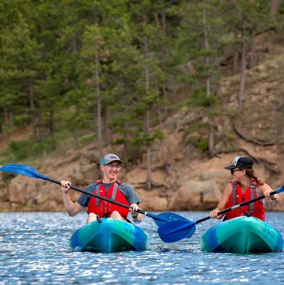 Two students kayak on a lake together.