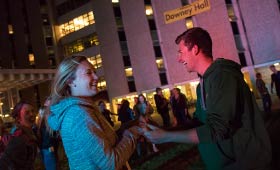 Students swing dance in front of the dorms at night.