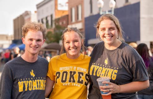 Three students pose together downtown.