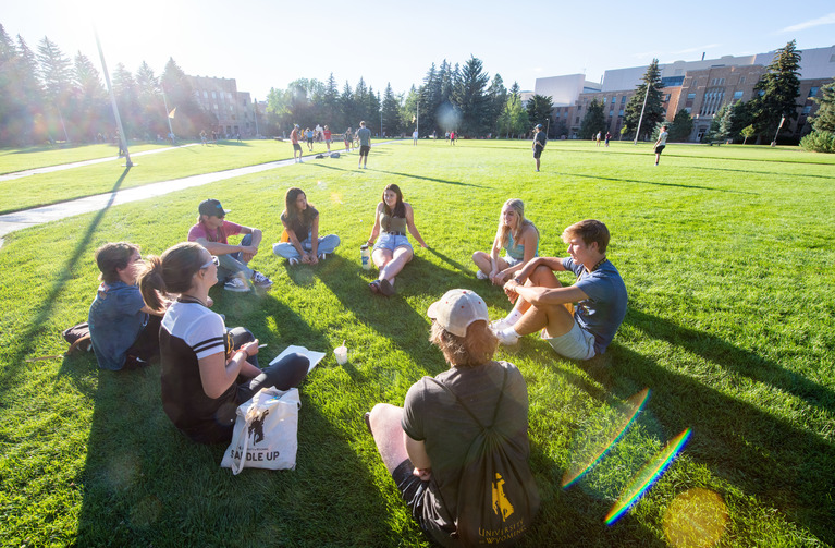 A group of students sit together on the grass in Prexy's Pasture.