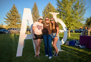 students in front of thier sorority letters
