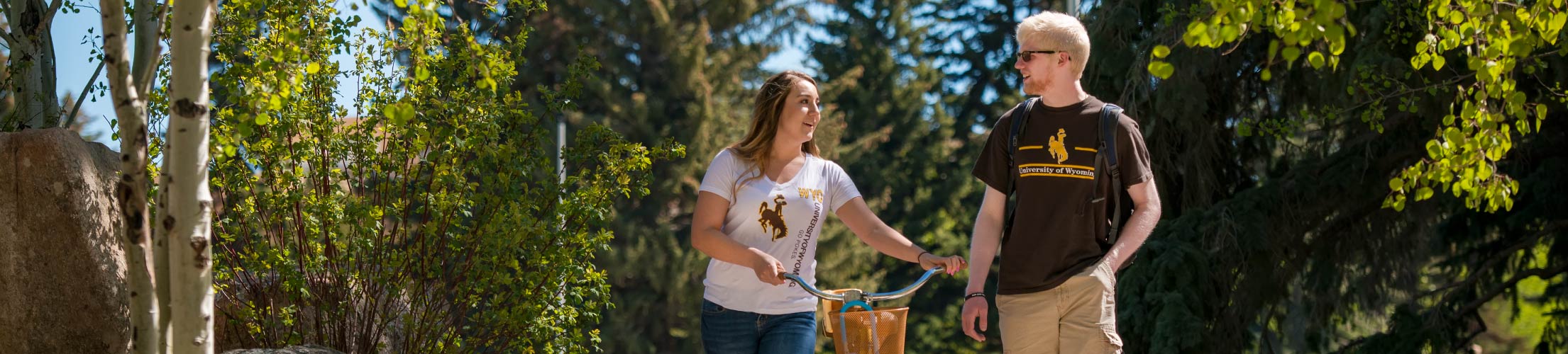 Picture of students walking together with a bike on campus.