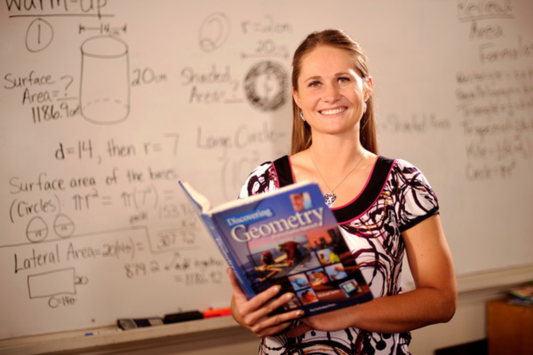 Teacher poses in front of white board
