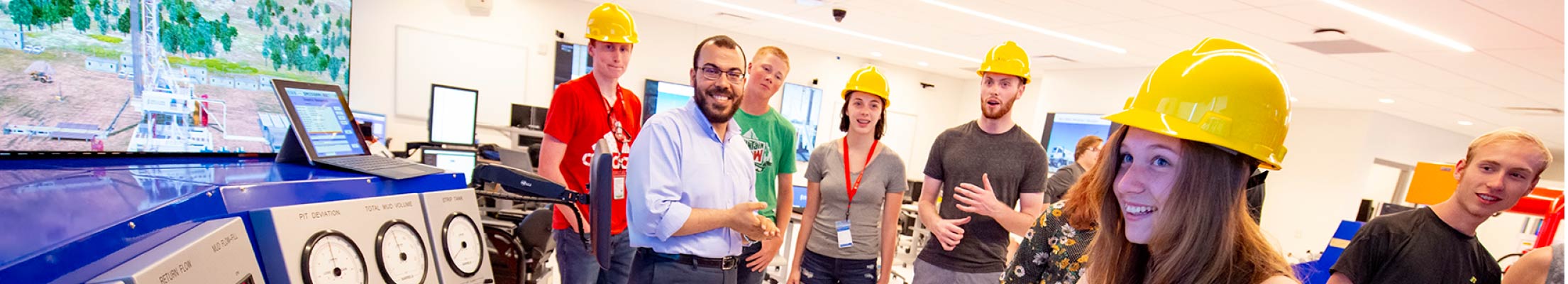 A group of students gather around drilling simulator