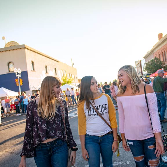 A group of students walk together downtown while laughing.