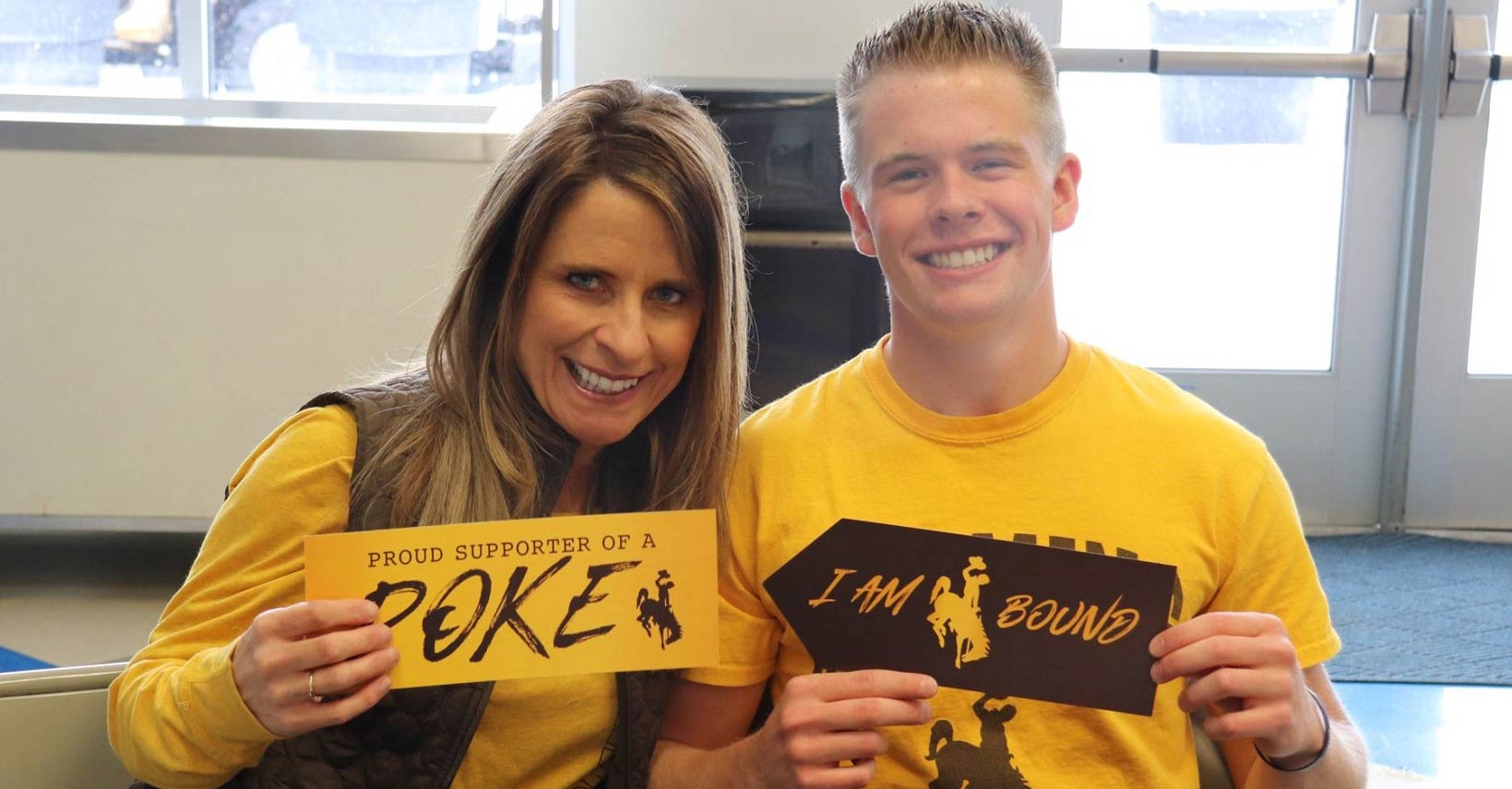 A parent and student pose for a photo with UW signs