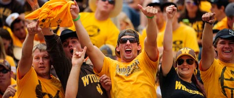 A group of students cheer in the football stands.