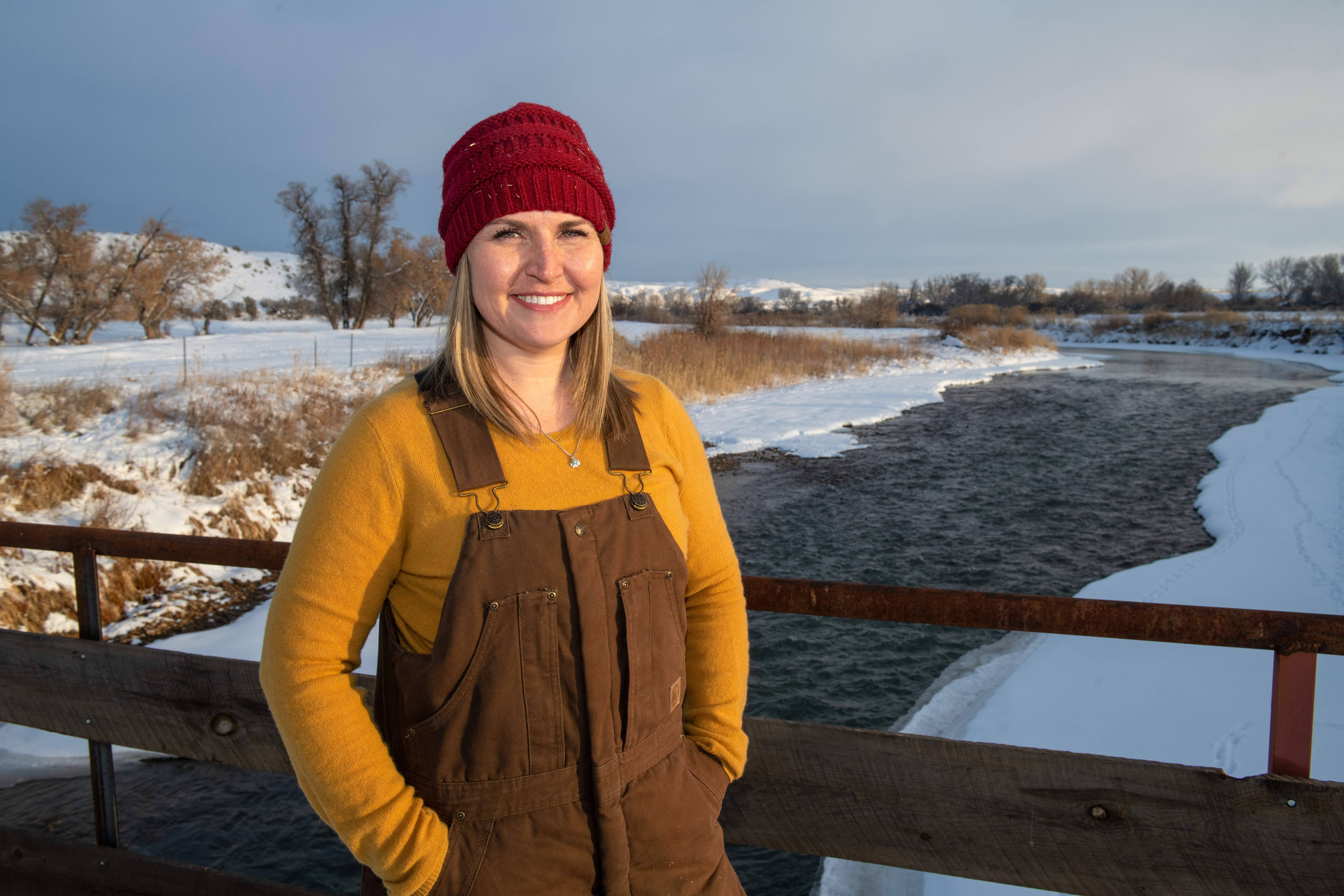 A student stands in front of a stream in the winter