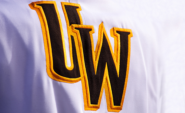 an embroidered logo of the UW letters in brown and gold on a white uniform