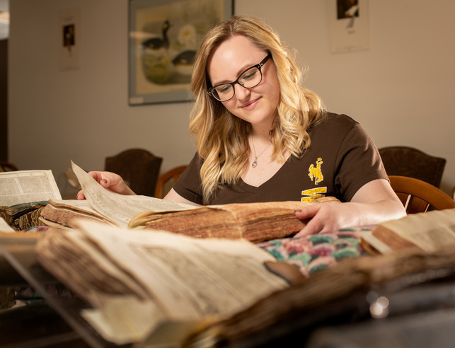 A student researcher examines an old book