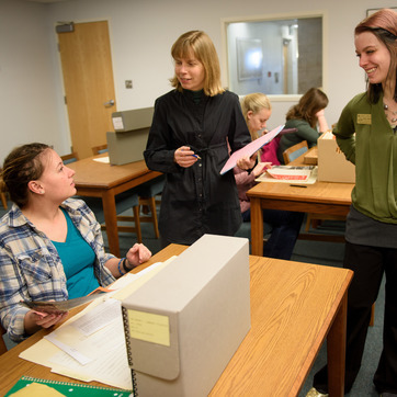 Two American Heritage Center employees help a student with their research project at AHC