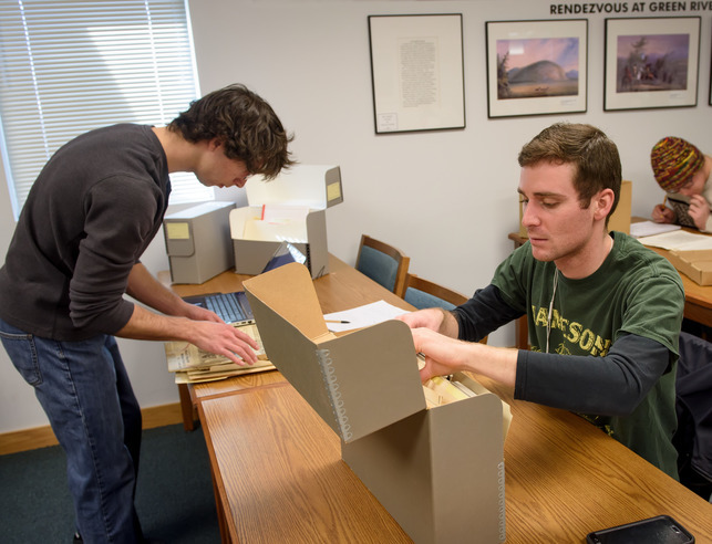 A student looks through a box of archives at the American Heritage Center