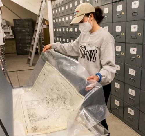 anaconda-maps help up over a table by an archivist