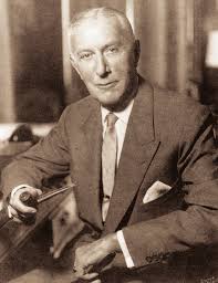 George Rentschler sitting inhis library holding a pipe.