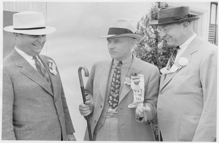 2 oil men in suits, wearing fadora hats, smiling at the prospect of making lots of money