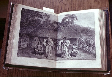 Black ink sketch across two pages of a book of 2 native men and 2 native woman dancing in fornt of a hut house with crowd of onlookers seated.