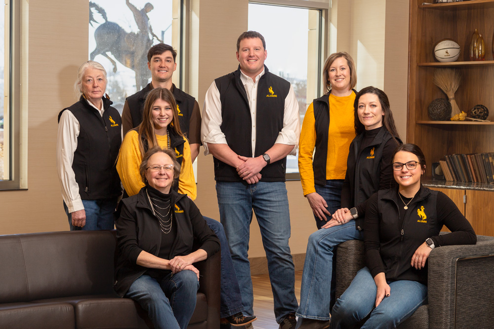 UWAA Staff sitting staggered on rock in front of Marian Rochelle Gateway Center