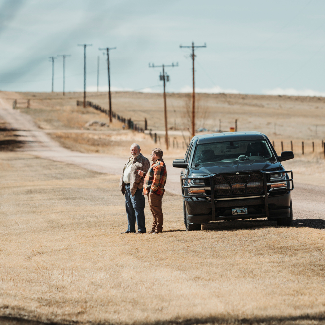 Two men standing by a truck in a field
