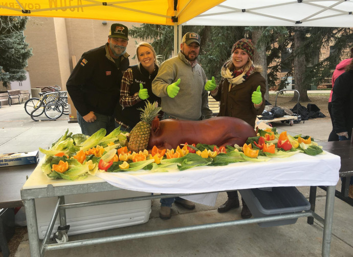 Four UW Food Science Club members stand behind a roasted pig at the annual homecoming roast. 