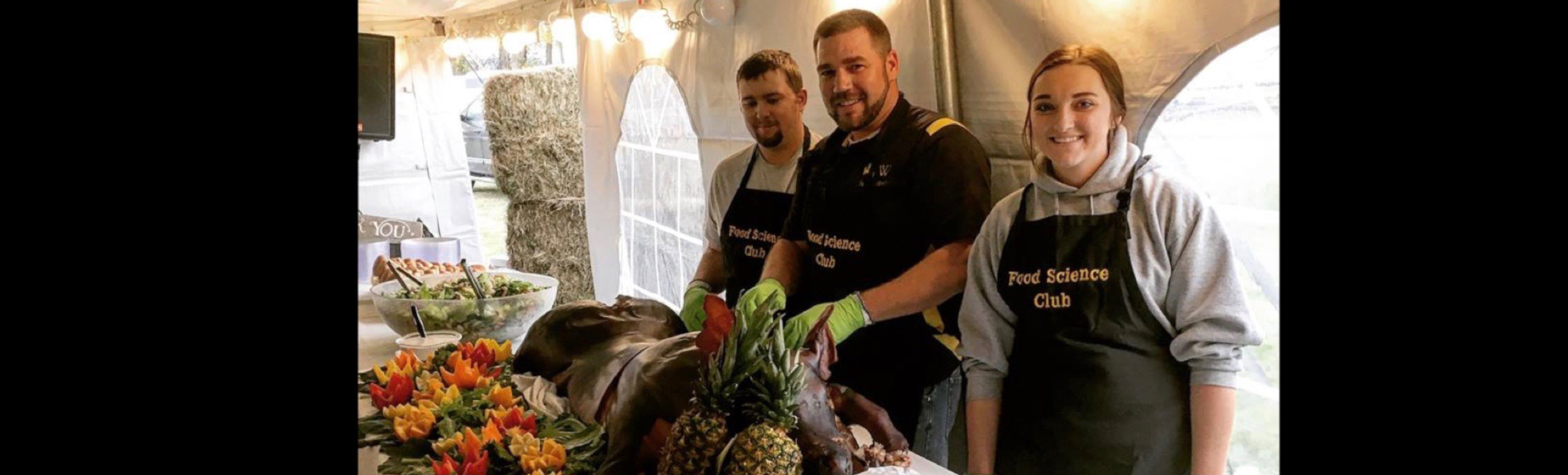 Advisor, Kelcey Christensen, and students, Brady Springer and Cedar Anderson, stand behind the pig that was roasted for the 2018 Ag Day BBQ