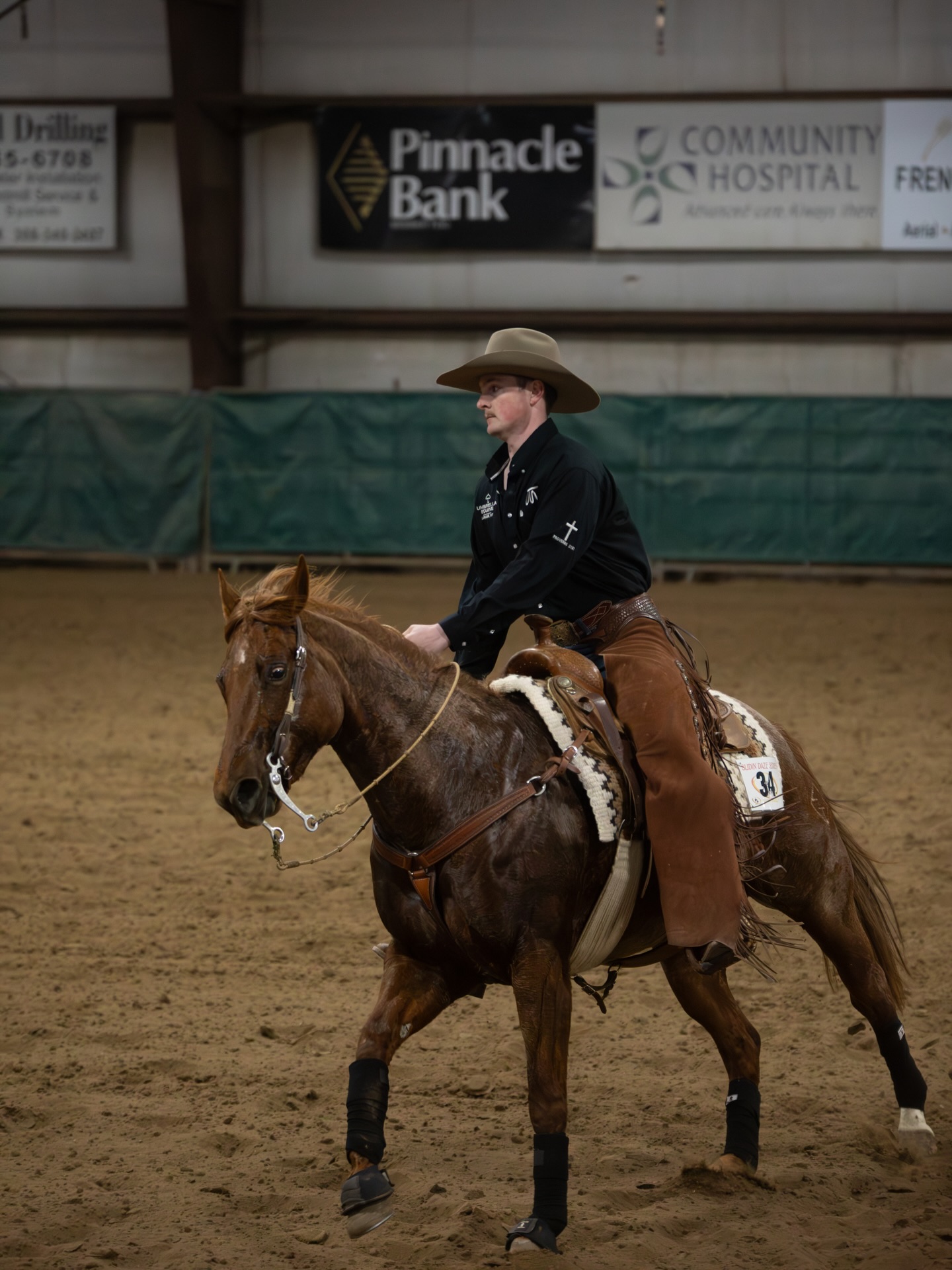 student sitting in a slide atop a horse in an arena