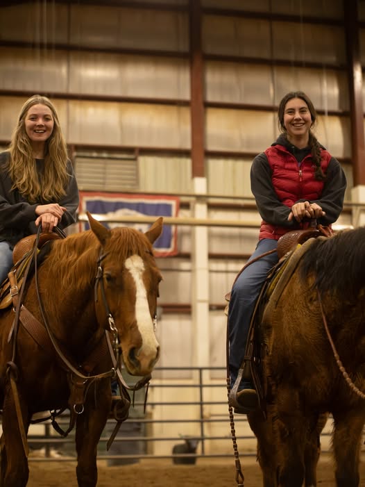 student dragging a bag behind a horse in an arena